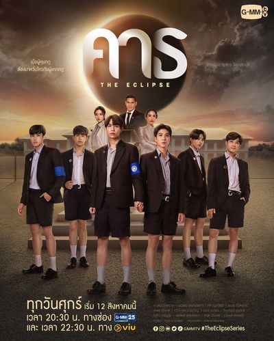 Numerous people stand facing the camera. The six in front are in a line and are all wearing the same uniform. The uniform is a black suit jacket over a light button-up shirt, black shorts, shin-high socks and black shoes. The first and third of the six also wear a blue arm-band over their suit jacket. All six have light skin and short dark-brown hair. Behind the line of six are three more people, standing slightly higher in a triangle formation. The two in the front of the triangle wear light gray pantsuits and have light skin and long hair which is pulled back. The person in the back of the triangle wears a black suit and tie with a white button-up t-shirt and has light skin and short black hair. Behind all the people is a fence and a large brick-built building. Above all of this is a dramatic solar eclipse in the middle of a cloudy sky.