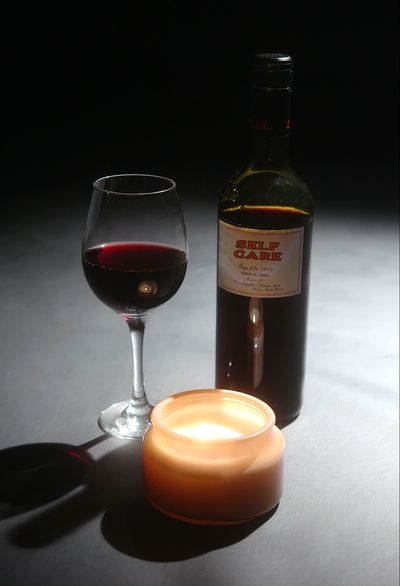 Film poster depicting a bottle of wine with the film's title "SELF CARE", a candle, and a glass of red wine, shot in studio on a black background.